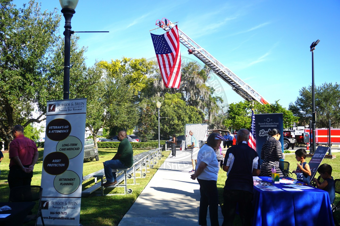 The American flag is swinging in the air and is stabilized by the fire truck ladder