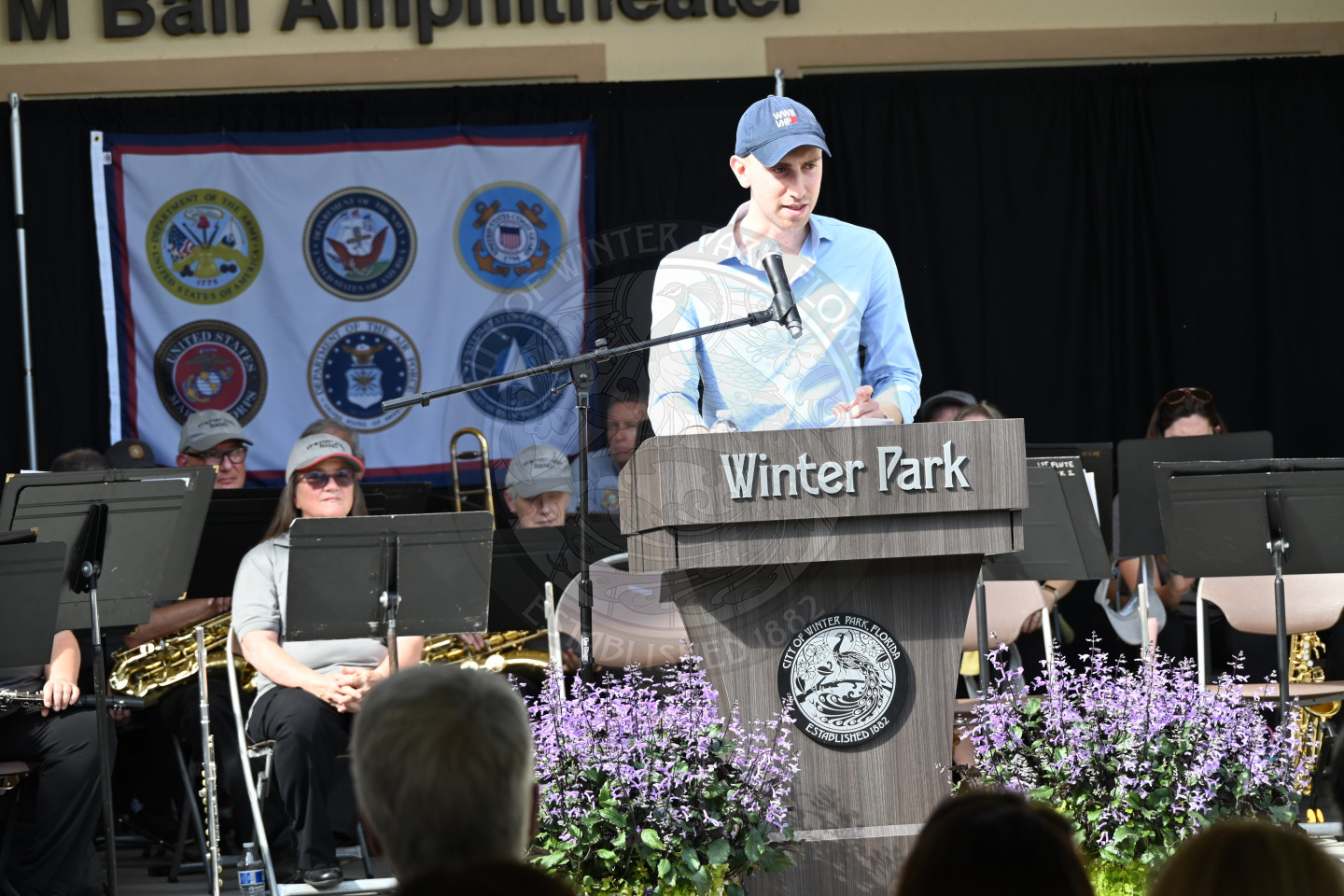 A man speaking about veterans to an audience while standing behind a podium.