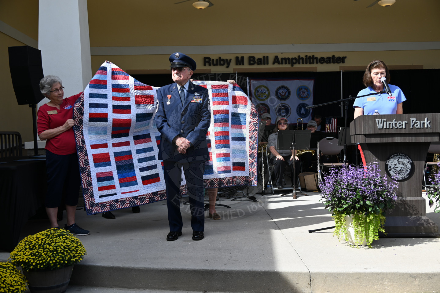 A World War II Veteran standing on a stage accepting his quilt of Valor. 