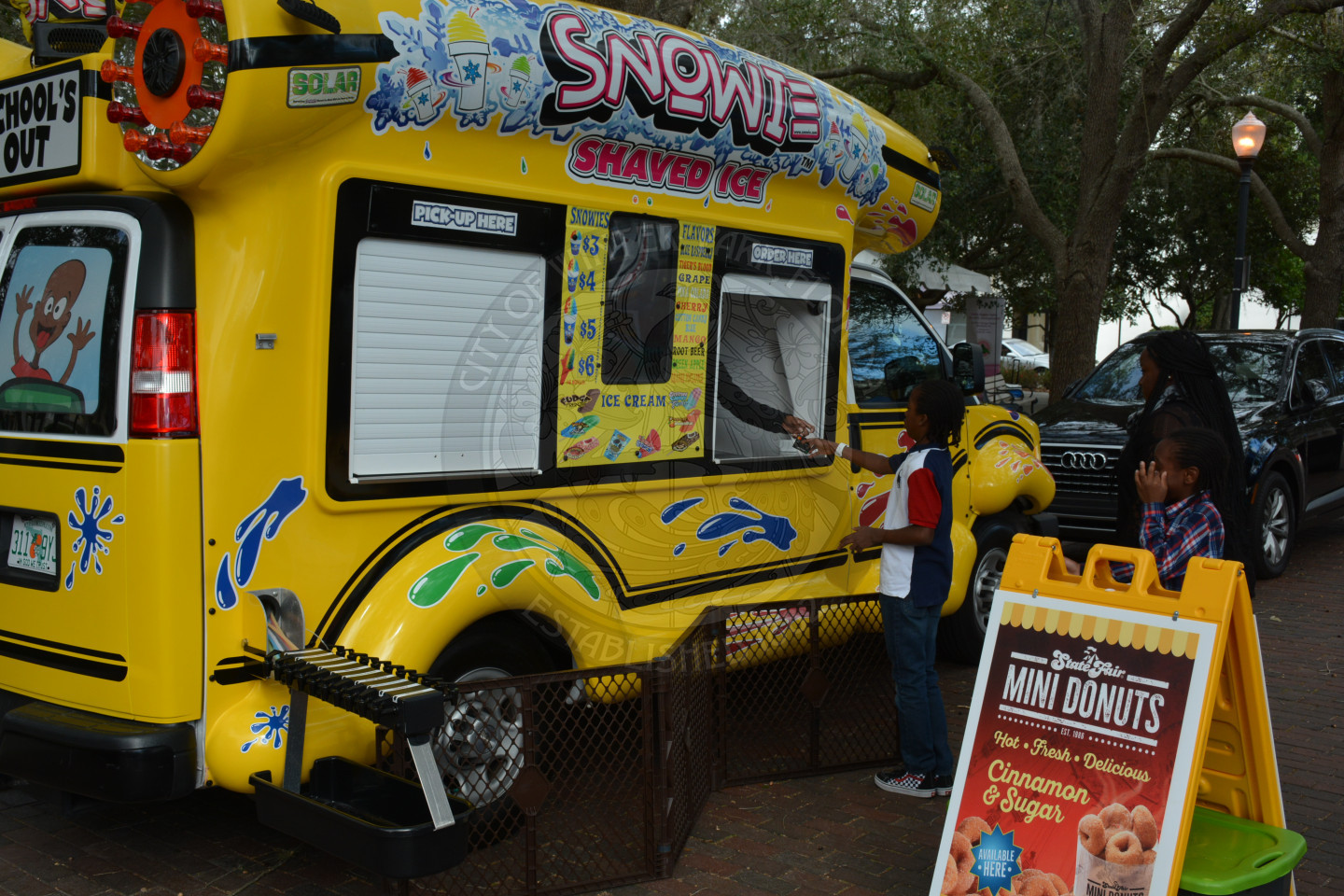 Snow cone vendor with two guests buying snow cones