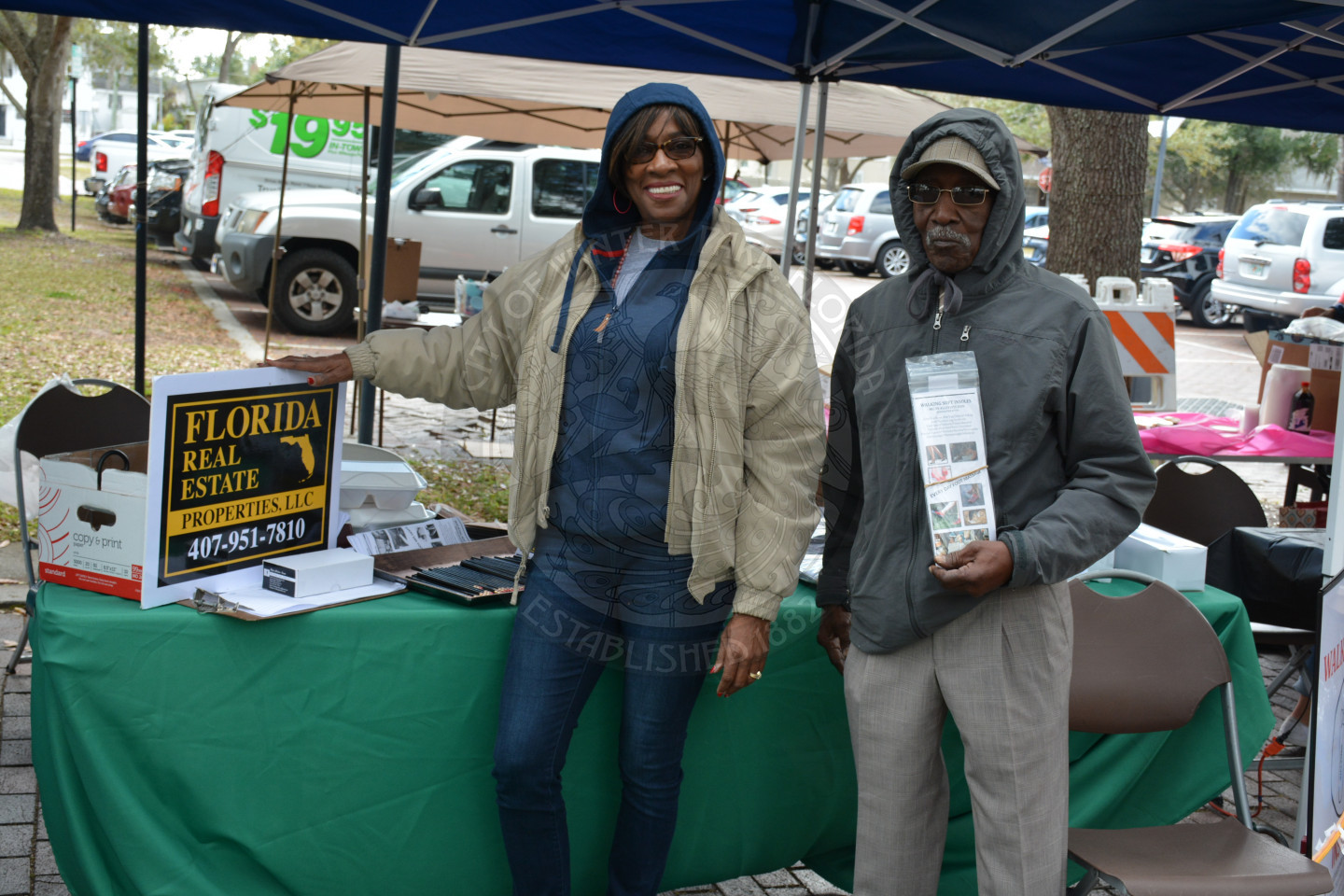 One female and one male smiling in front of the Florida Real Estate Properties vendor booth