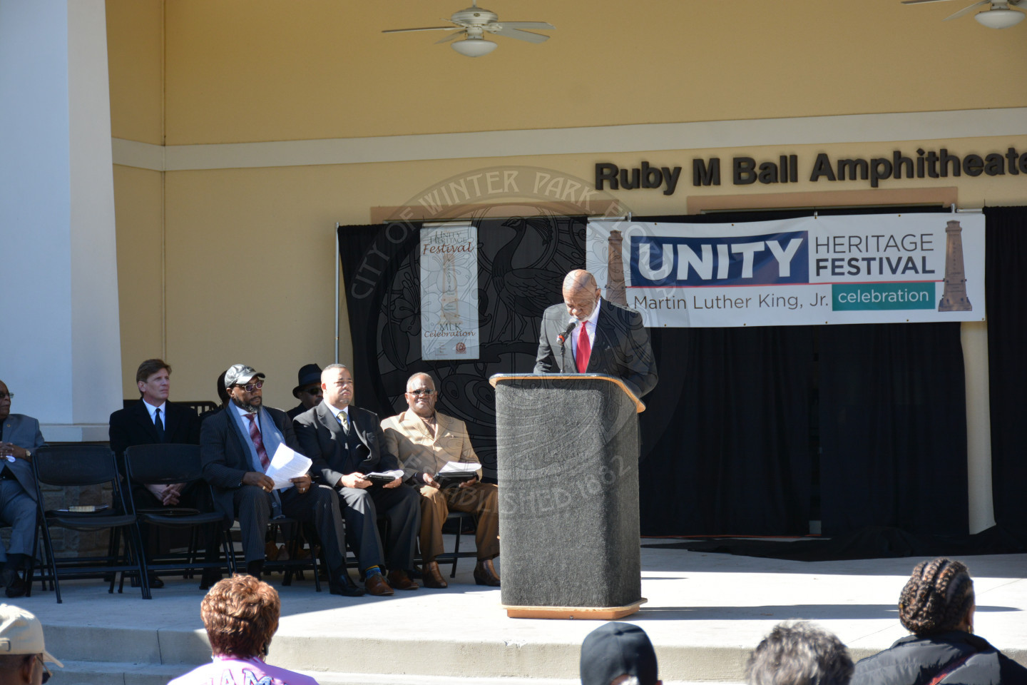 front view of stage with VIPs seated on the stage and one gentlemen at the podium