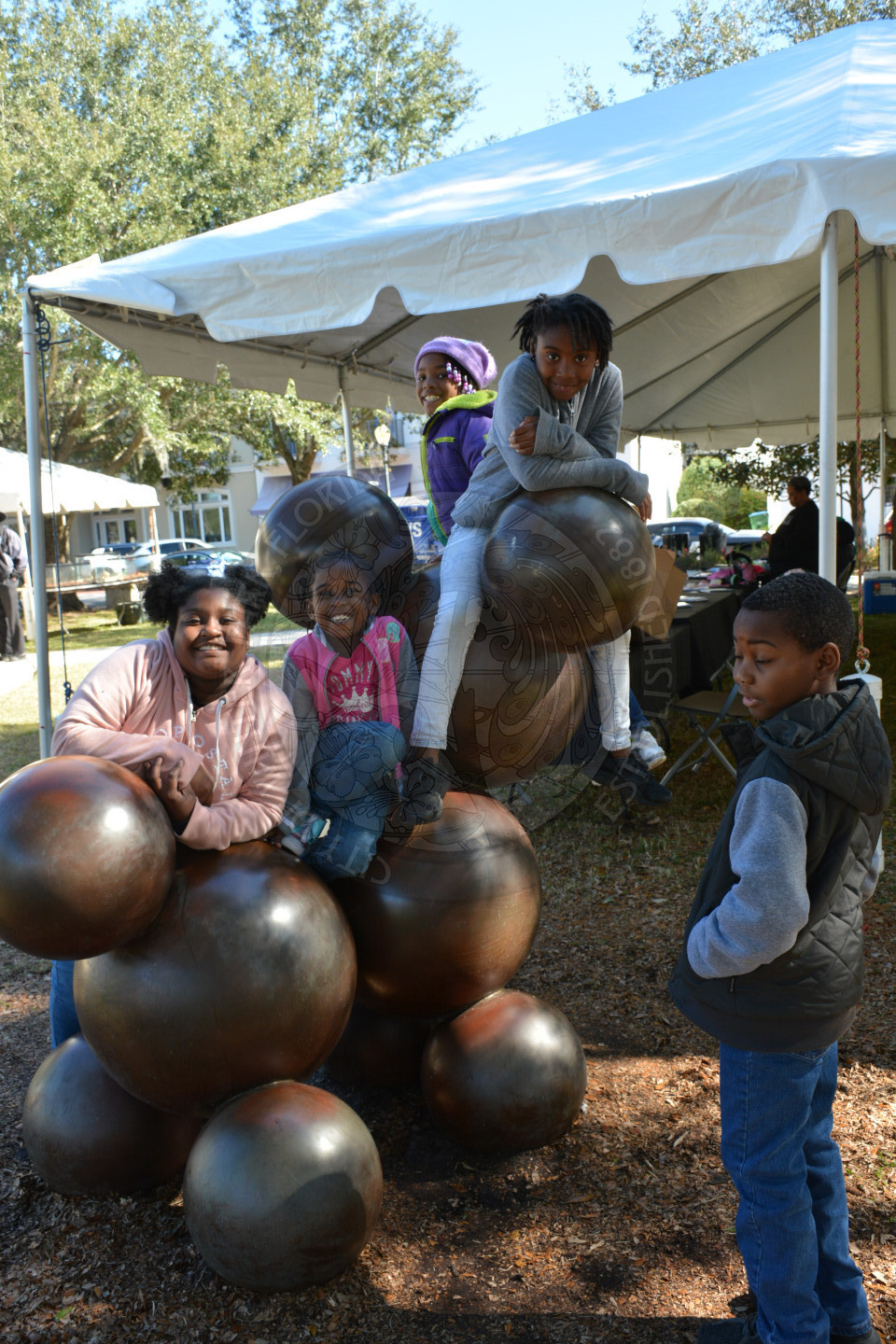 four young children playing atop the molecular dog sculpture