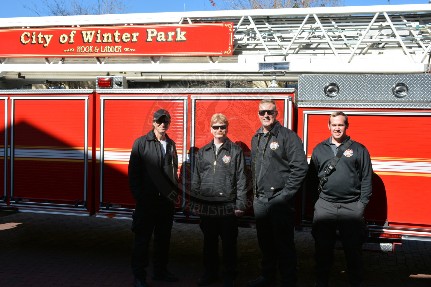 Four firefighters smiling in front of Engine 61