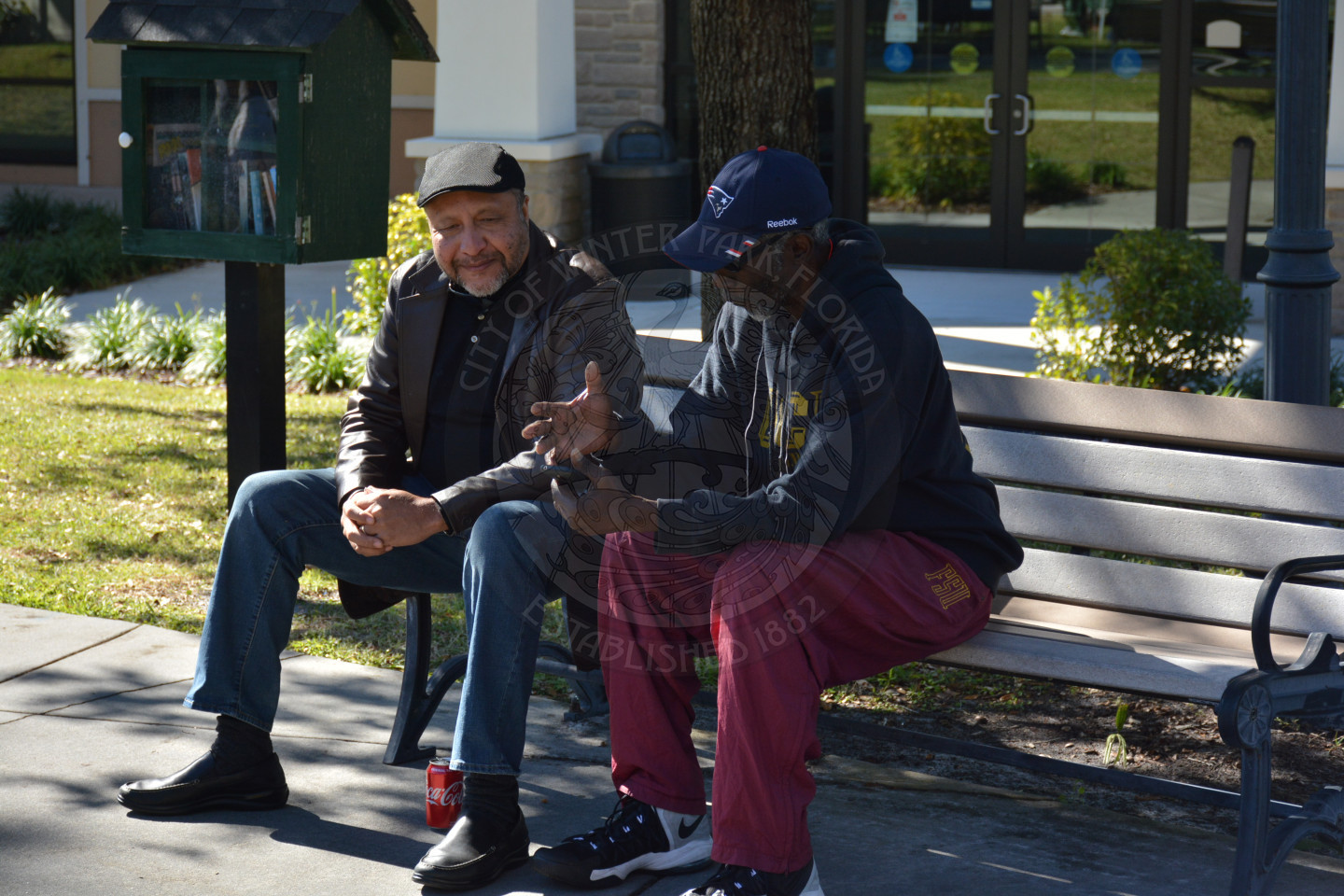 Two gentlemen seated at a park bench talking