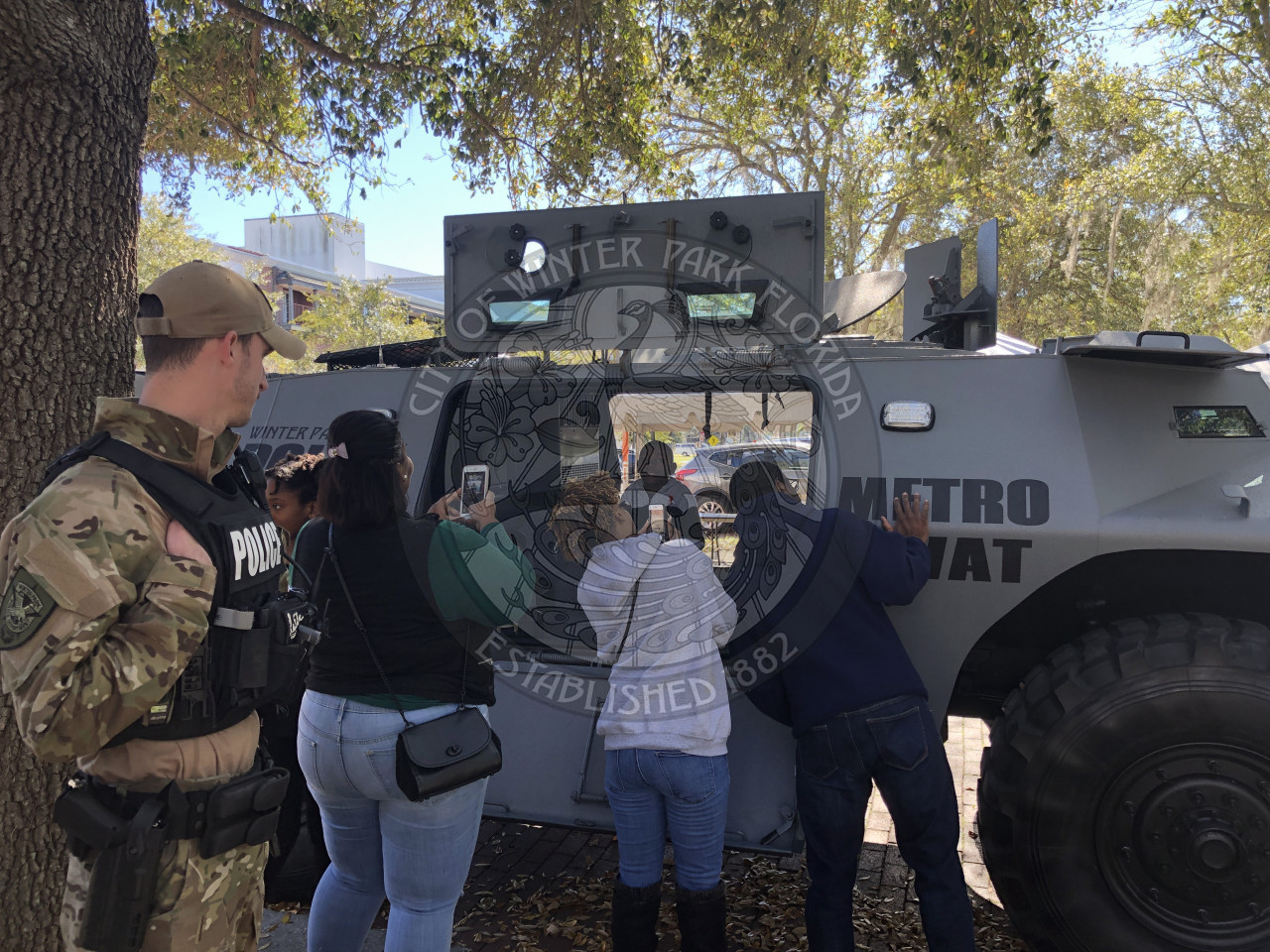 swat officer watching parents take photos of their kids inside a swat vehicle