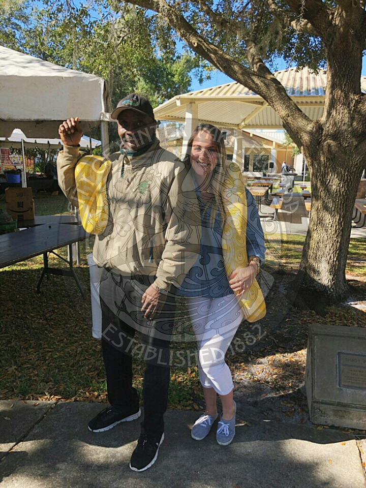 man and woman smiling and holding a large snake