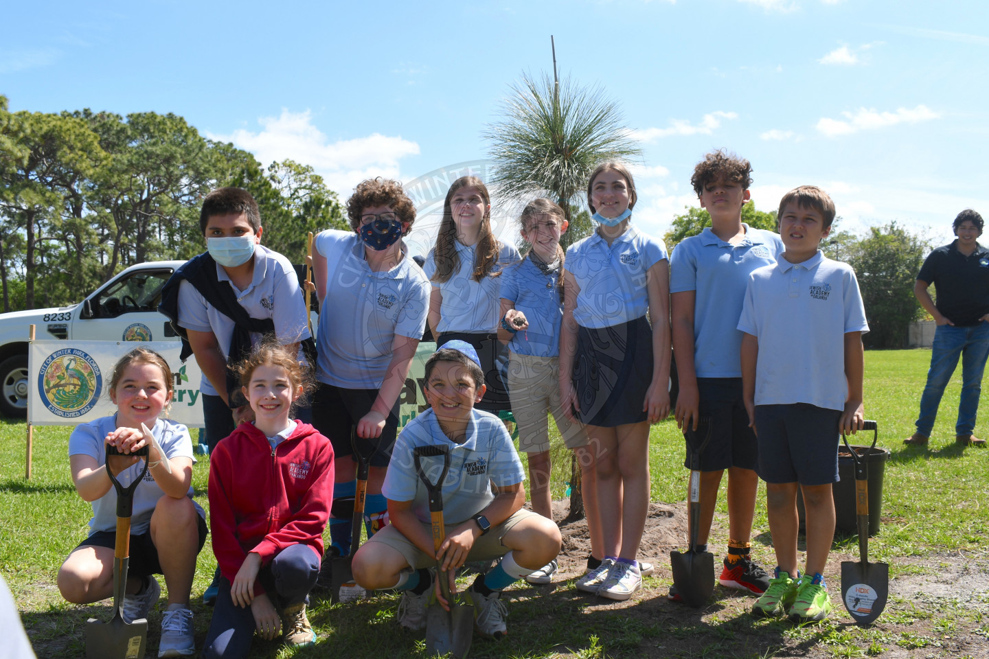 Group photo of kids smiling in front of the tree they planted