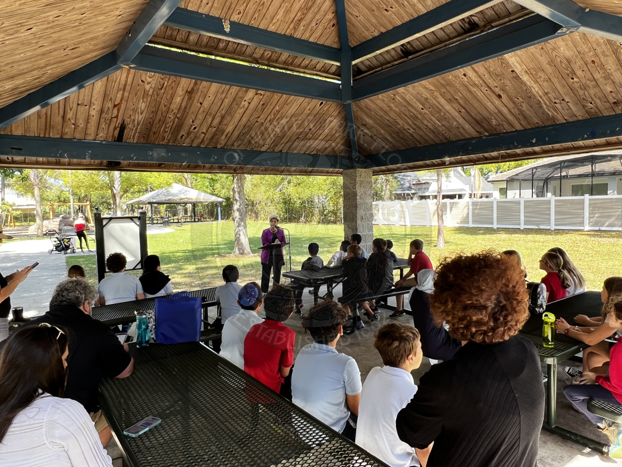 Commissioner Carolyn Cooper speaking in front of group of kids underneath pavilion