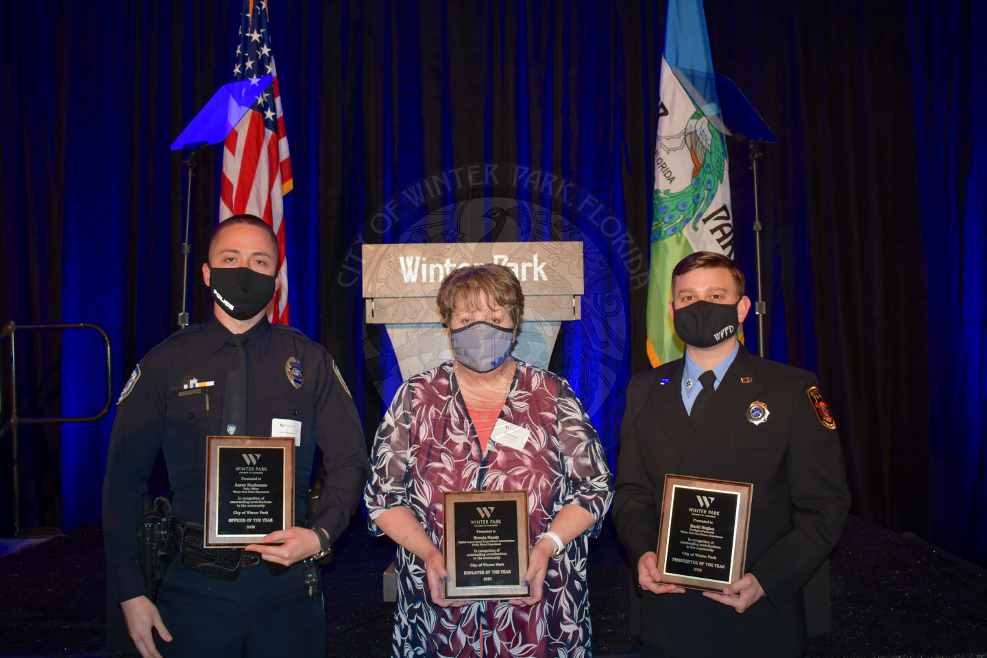two men and one woman standing together with their employee of the year plaques