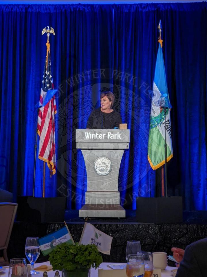 Winter Park Chamber President Betsy Eckbert on stage behind the podium