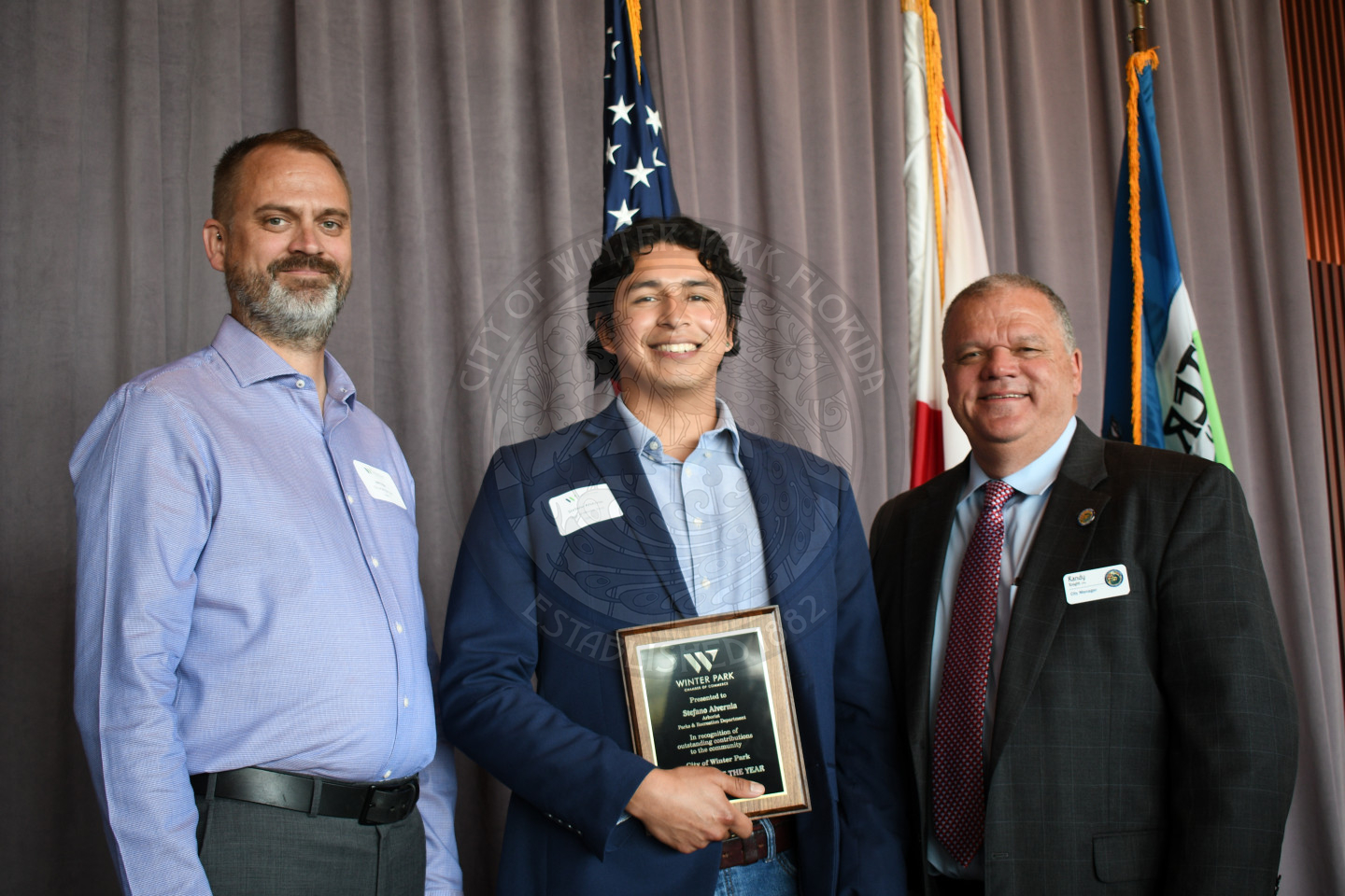 Man holding employee of the year plaque with another man and City Manager Randy Knight