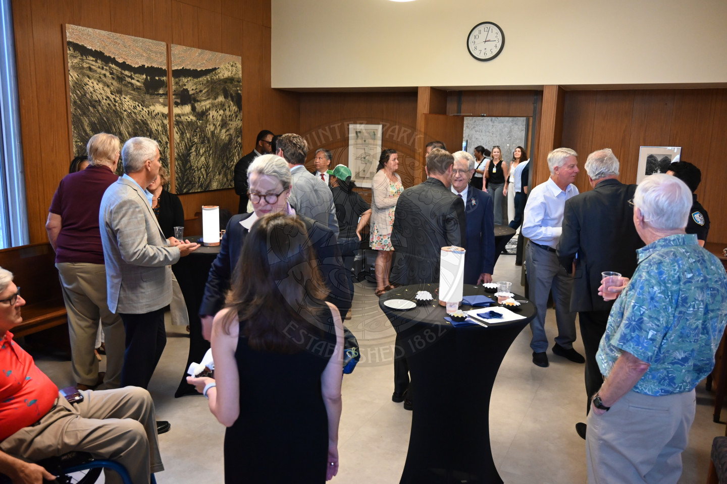 people mingling while drinking and eating cupcakes.