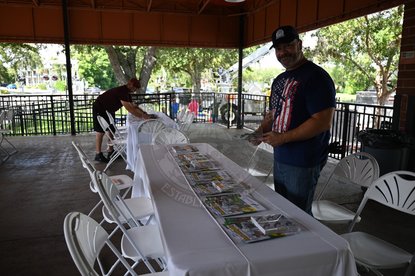 a man placing coloring book and crayons on tables outside.