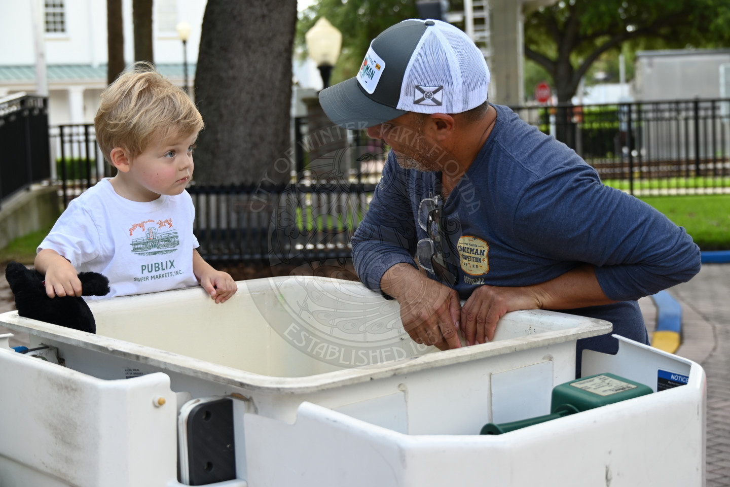 a man and a child hanging on the sides of the bucket in the bucket truck.