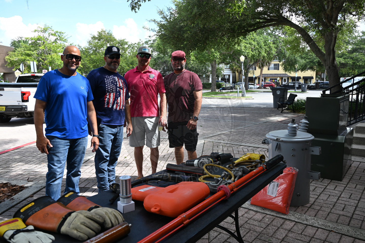 four men standing next to each other and in front of a table with electric utility gear
