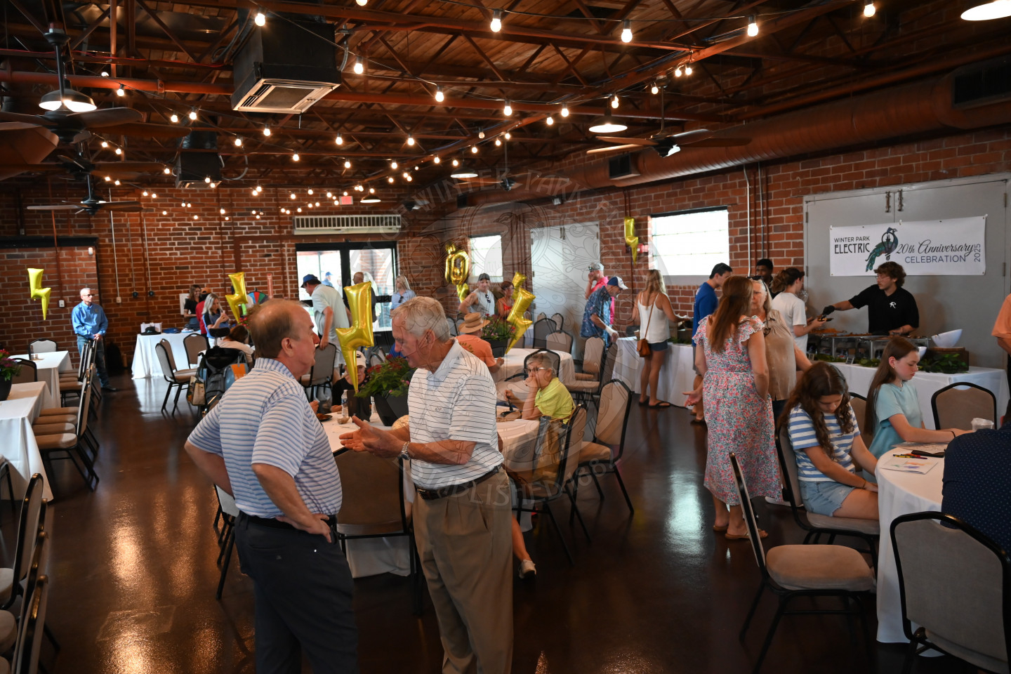 people mingling throughout the room and sitting at tables. 