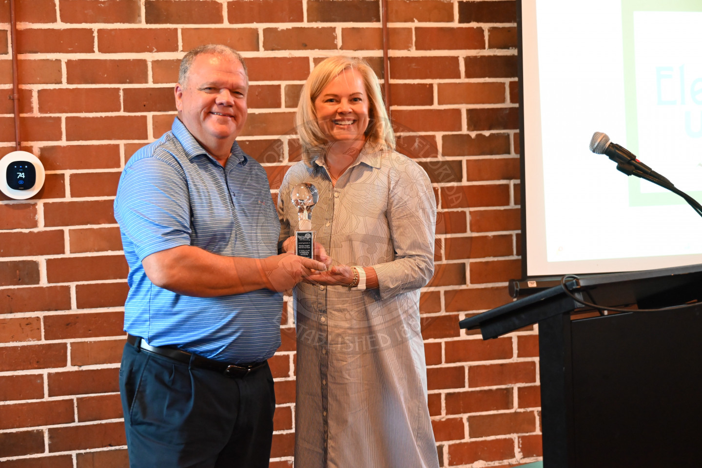 a woman and man standing next to each other holding an award.