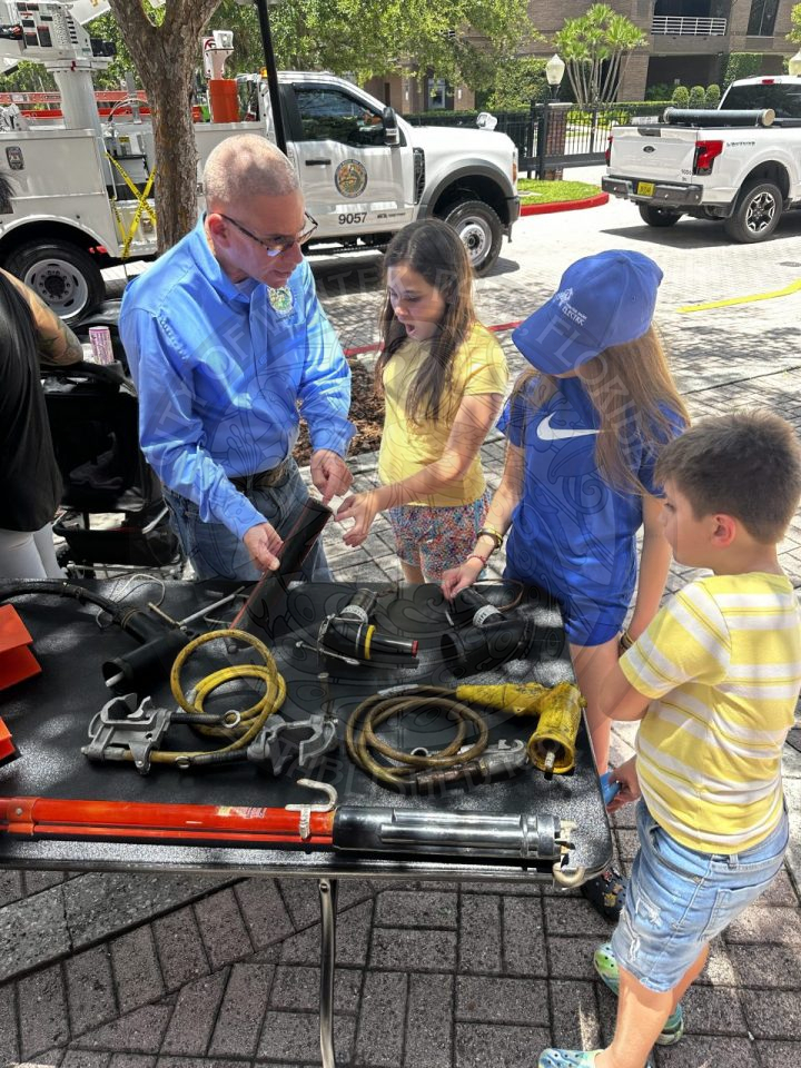 an electric utility deparment worker talking to kids about how some tools work.