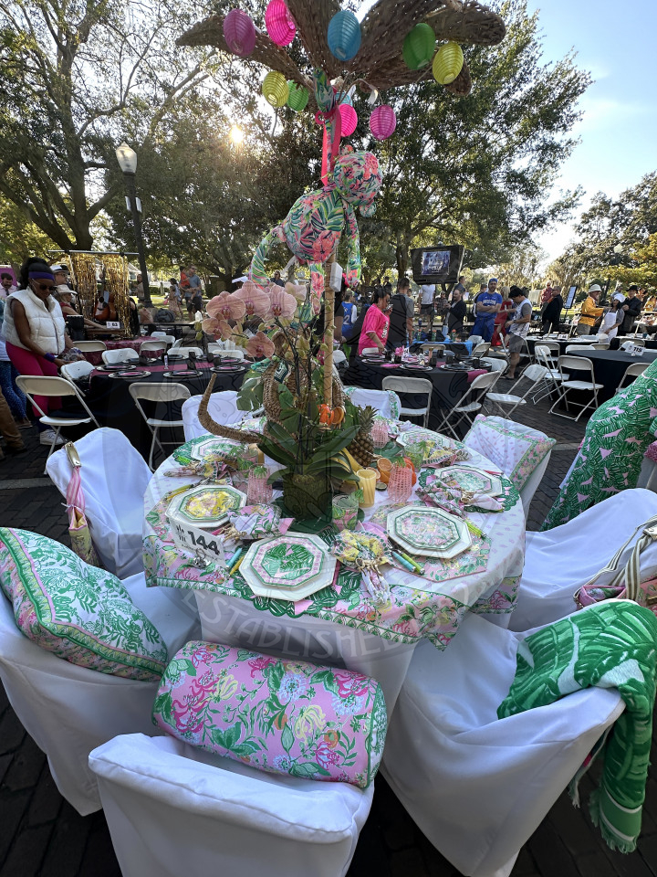 a Lily Pulitzer themed table with patterned table cloth, pillows, towerls, etc. on the table.