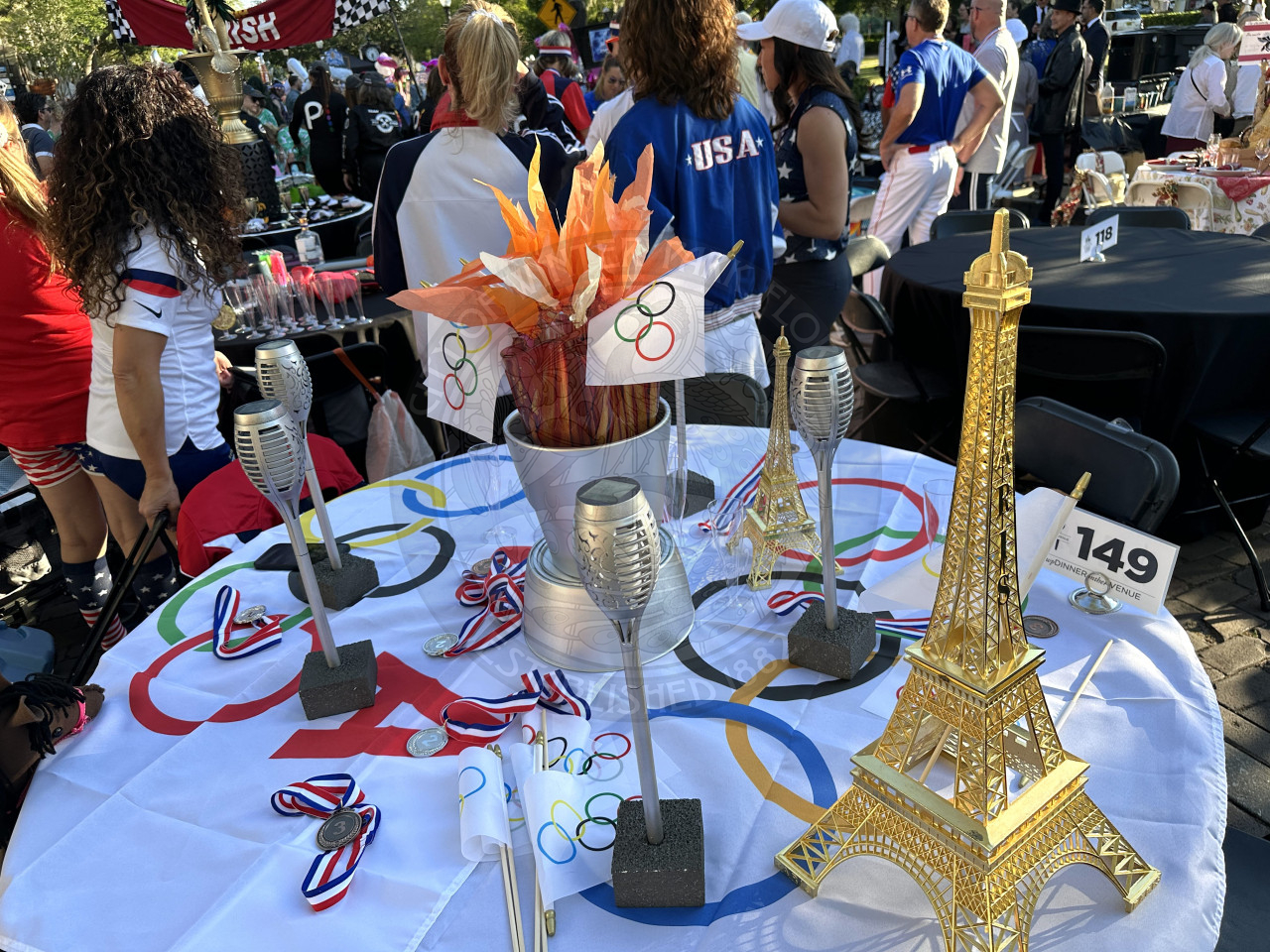 a paris olympic themed table. There is plastic medals and torches around the table with olympic hand flags.