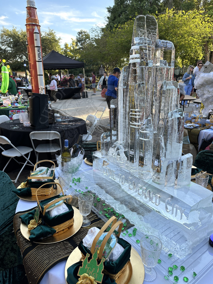 a table with an emerlad city ice sculpture on it. There are baskets with names on them placed around the table.