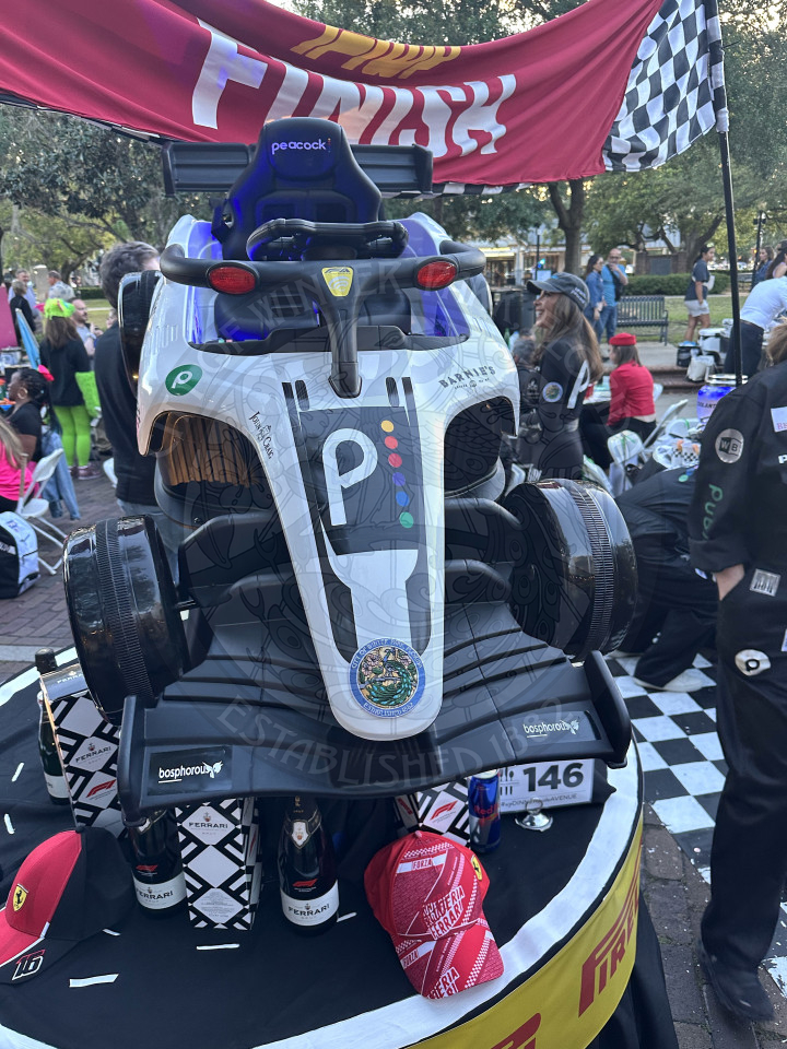a DIY made car with logos on it from Publix, Barnie's, peacock, city of winter park city seal, etc. on top of a table and above it is a banner that says "finish"