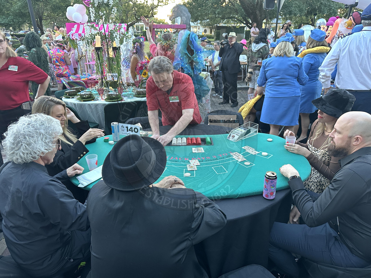 a poker table with 5 people playing poker and the dealer passing out the cards.