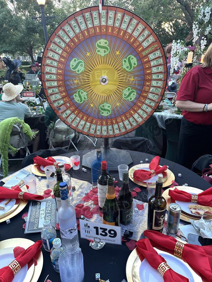 a table with a money wheel on it and bottles of wine with gold table settings.