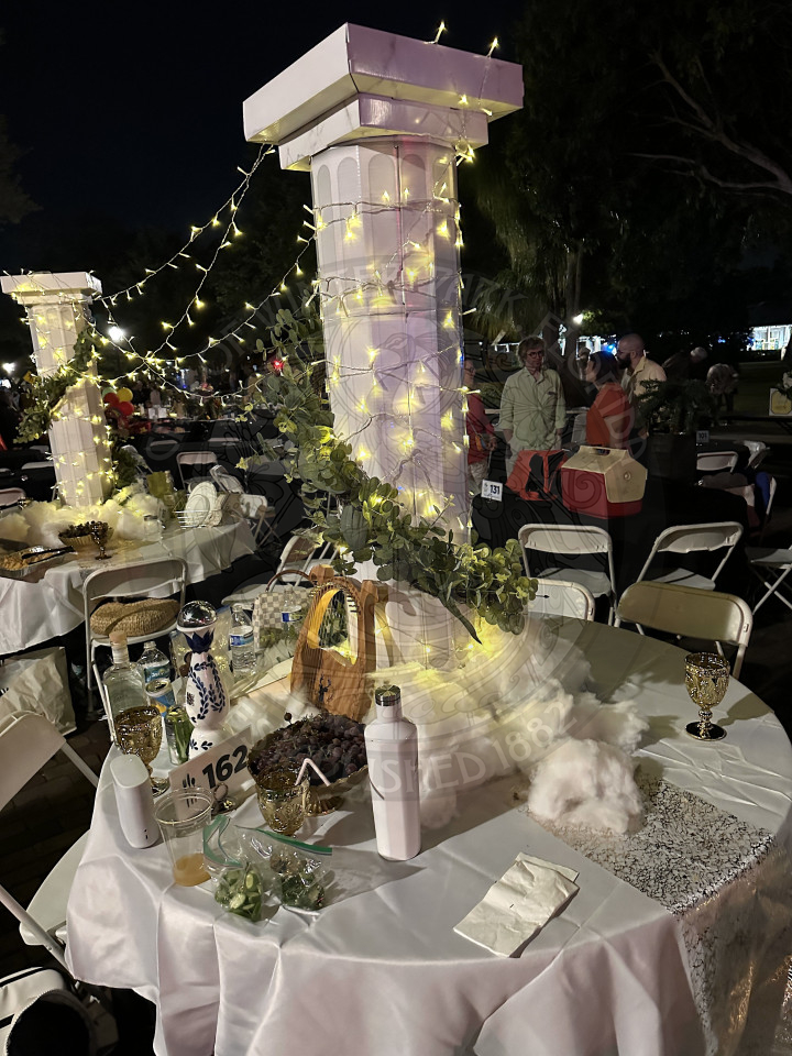 2 tables with a white boulders on each table and lights hanging on both of them. 