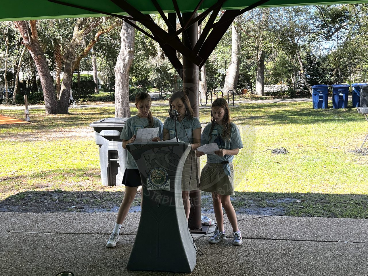 3 girls standing behind podium reading something off papers