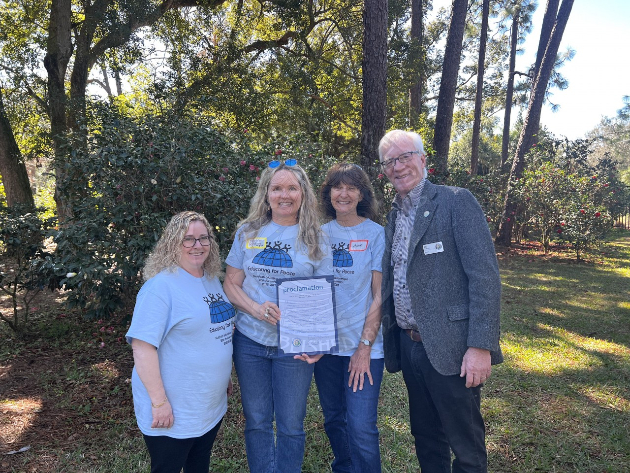 Three ladies and a man standing next to each other posing for camera smiling holding proclamation.