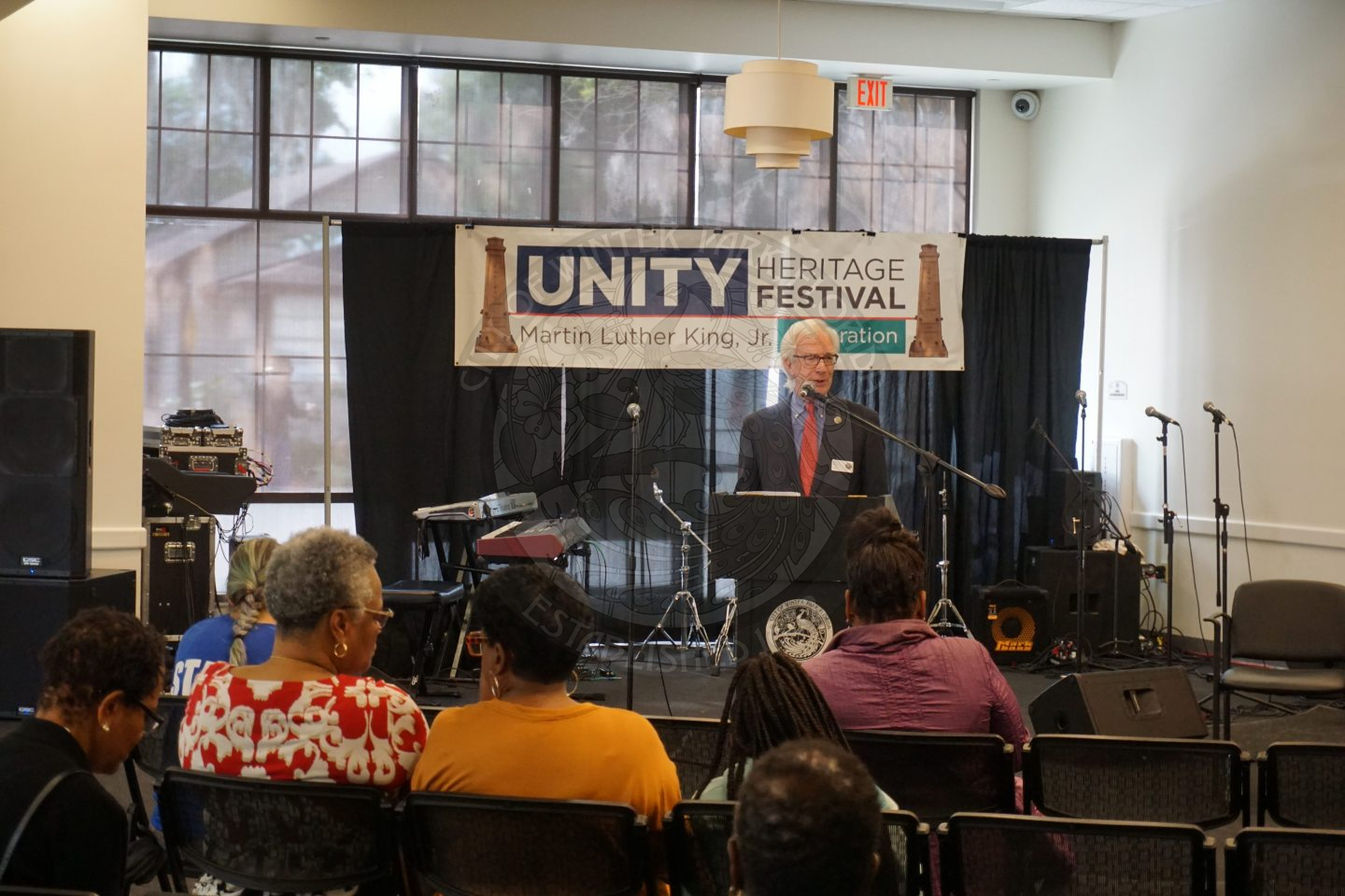 The mayor standing behind a podium but in front of a stage with a sign that says Unity Heritage Fesitval.