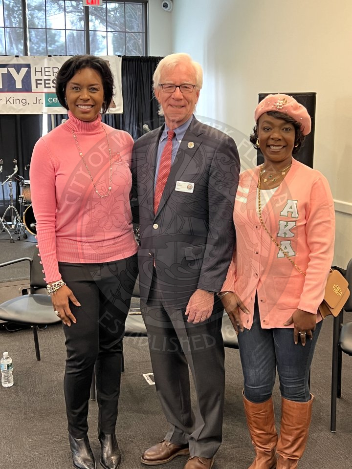 2 woman standing next to the mayor smiling.