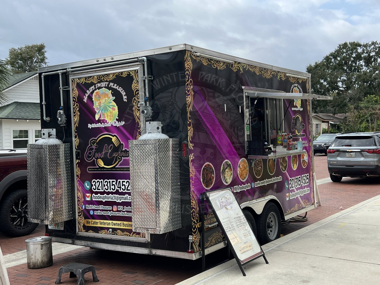 a food truck parked parallel in conjuction to the sidewalk.