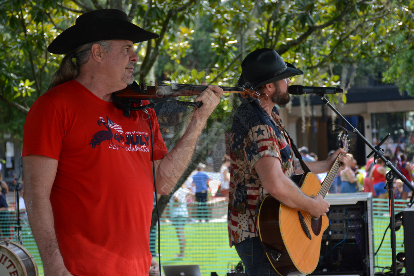 two men on stage playing instruments in cowboy hats