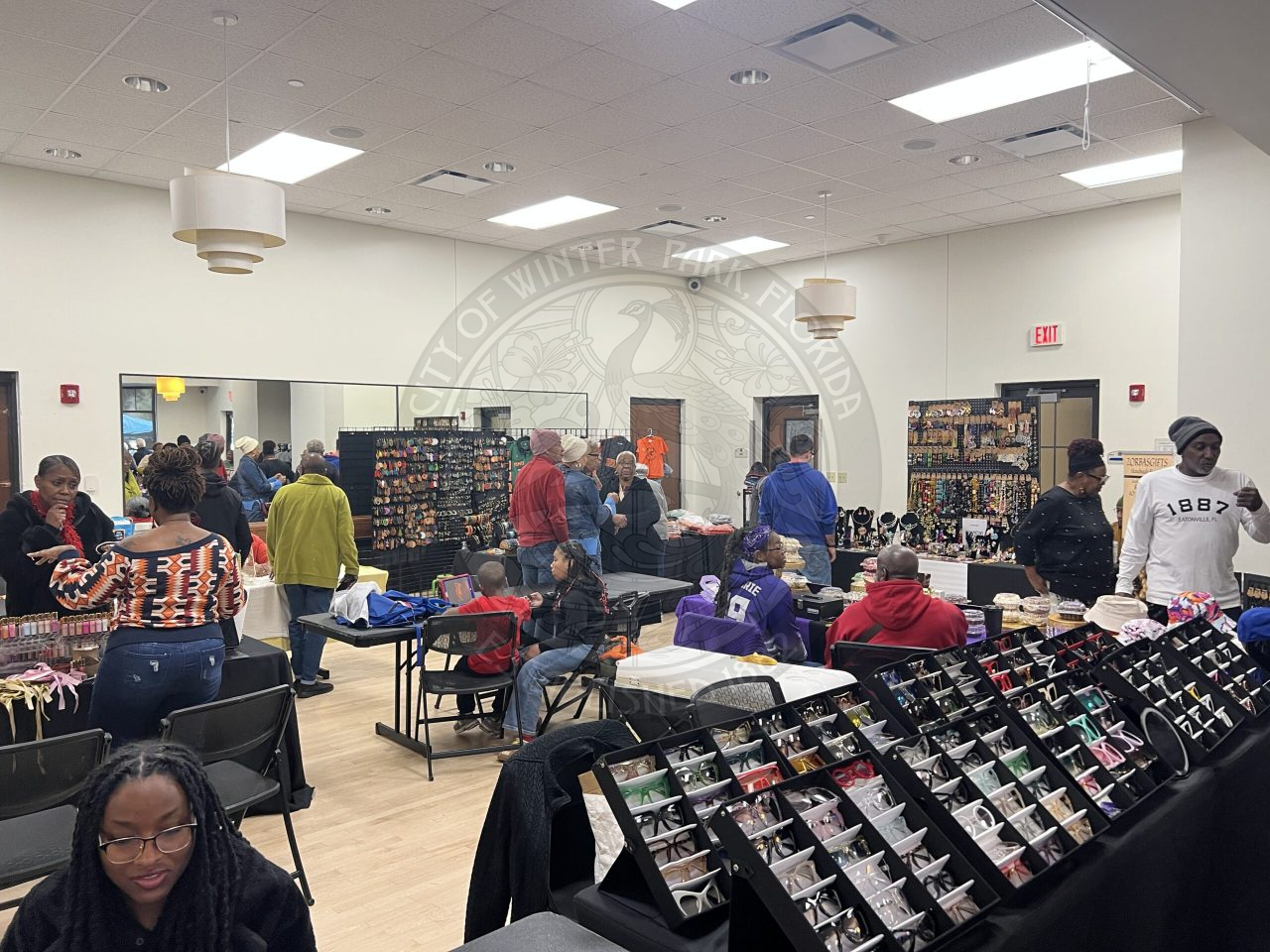 A room filled with products on tables and people walking around the tables looking at the products.