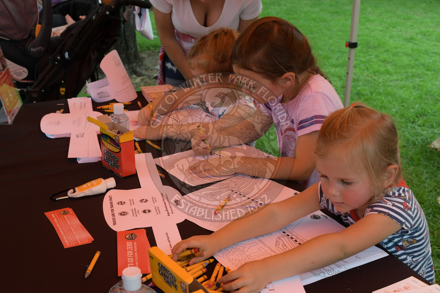 three girls coloring train conductor hats at the SunRail tent
