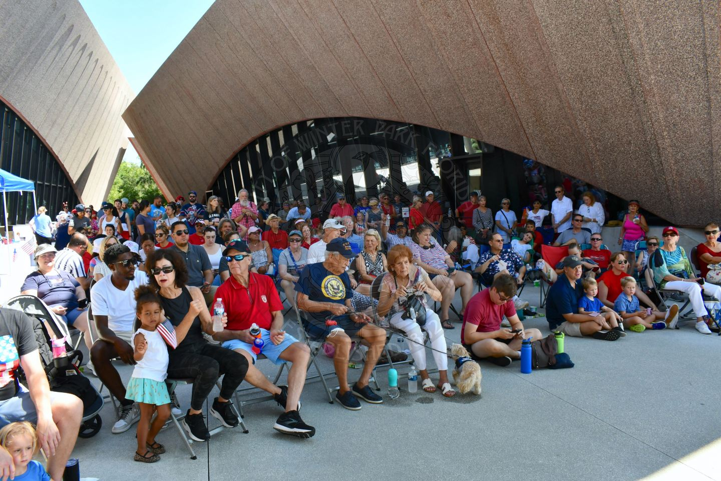 Crowd standing and sitting waiting for a musical performance to start