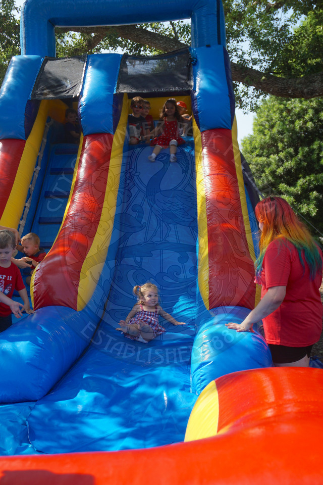little girl slididng down a bounce house slide and smiling