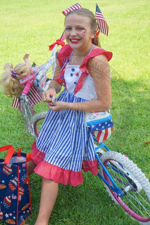 little girl wearing american themed clothes and bike sitting on her bike