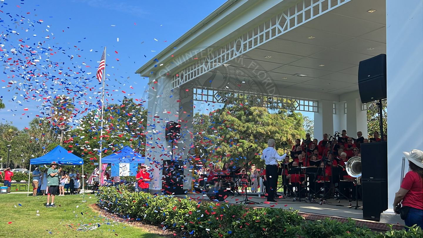 peices of confetti blowing in the wind in front of stage where a band is playing