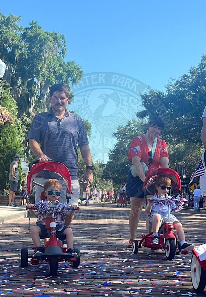a man and woman pushing their kids in their strollers for the bike parade.