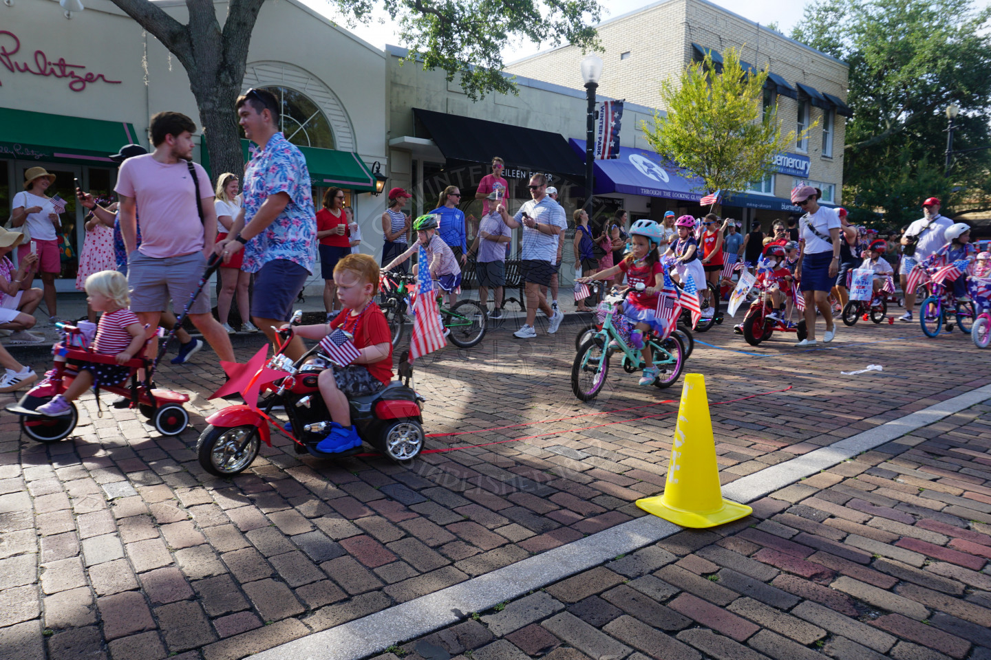 kids riding decorated fourth of july themed bikes riding on a brick road.