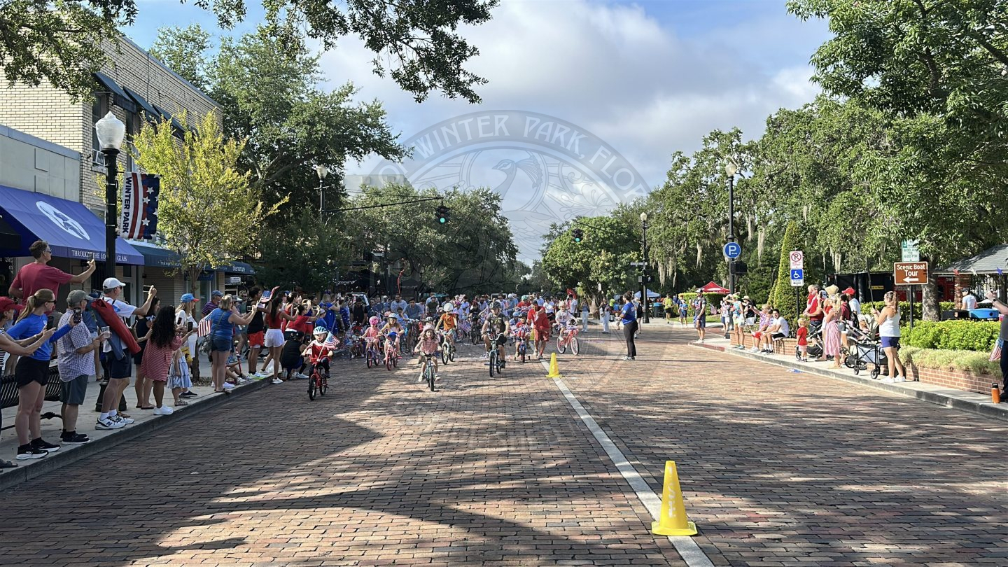 Ikids riding decorated fourth of july themed bikes riding on a brick road.