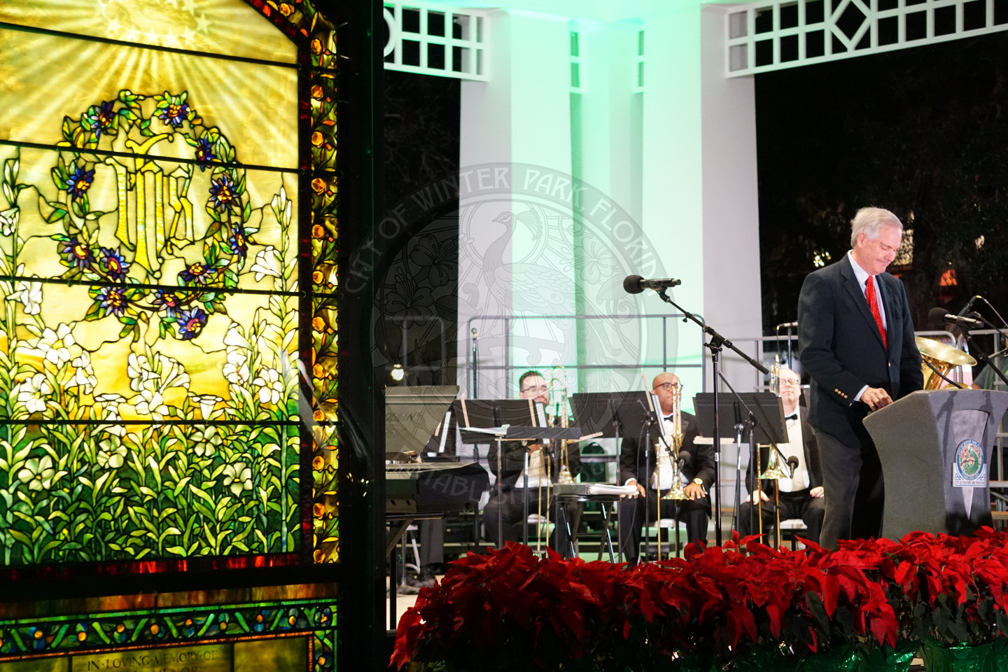 Man standing on the stage at Christmas in the Park speaking to people.