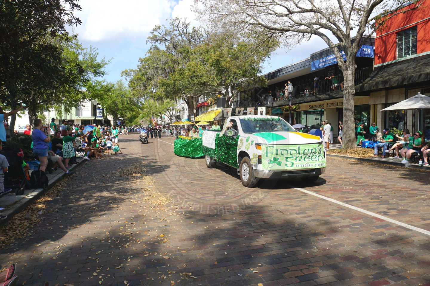 A truck with a trailer in the back decorated in tensil and a sign that says "Fiddler's Green"
