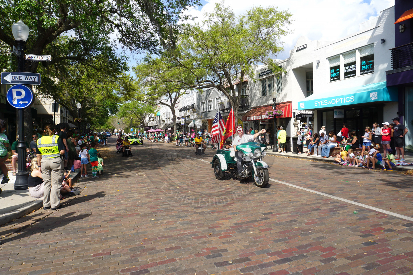 Veteran driving a three wheeler motorcycle waving to everyone watching the parade
