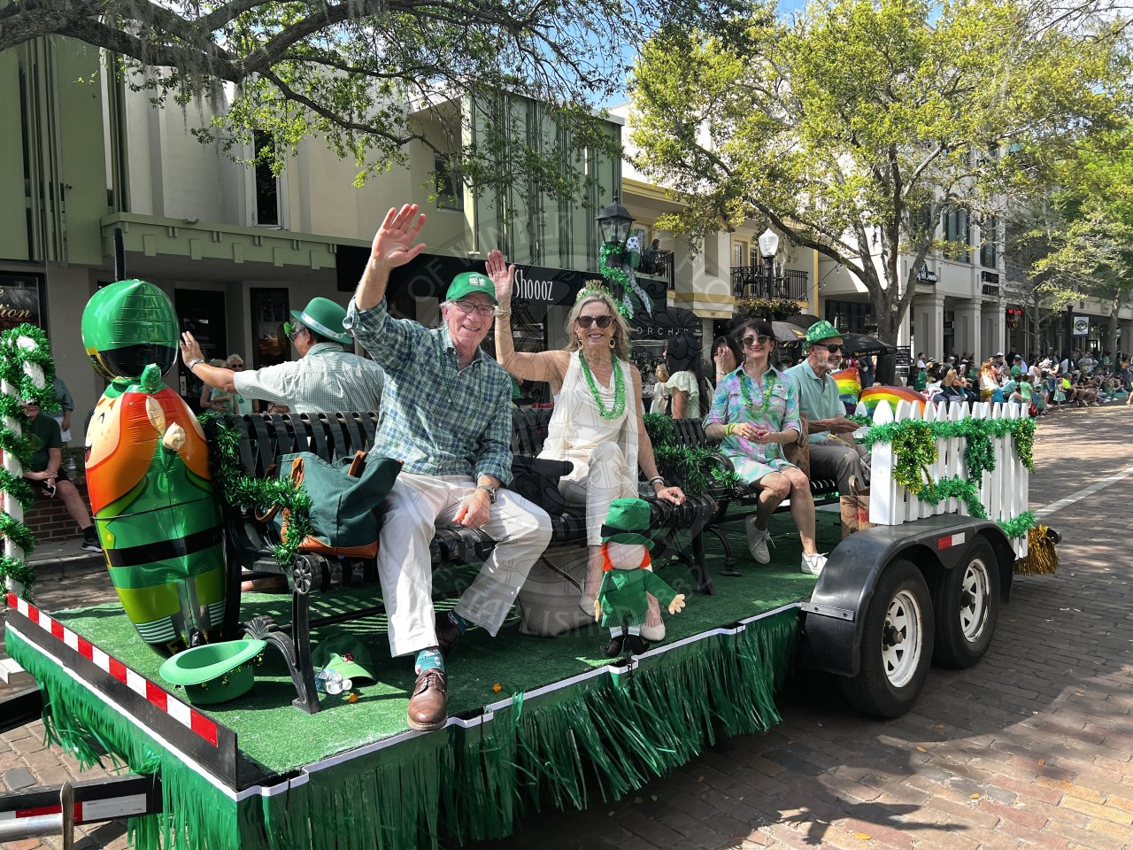 Mayor and his wife and commissioner and her husband on a parade float waving and smiling