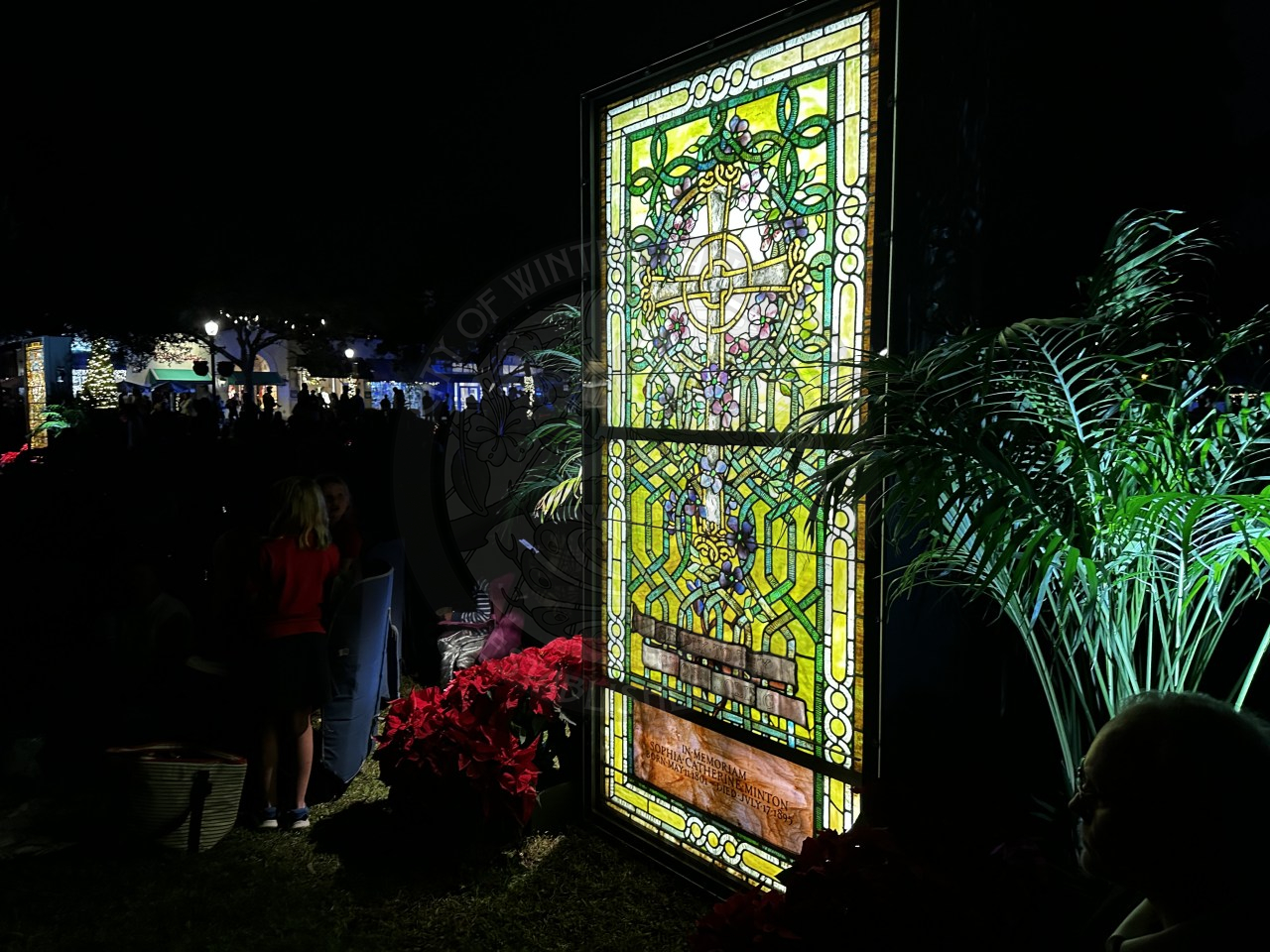 A yellow and green stained glass window with a cross on it.